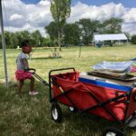 Kid dragging cart across grassy field