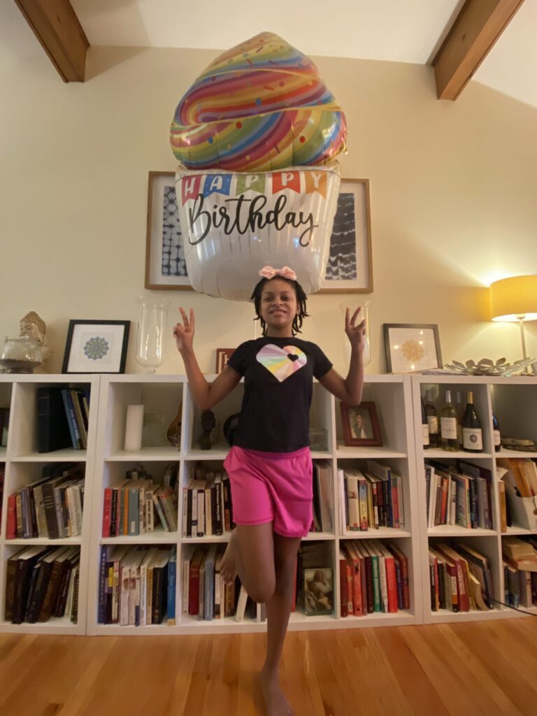 Child posing with birthday balloon indoors